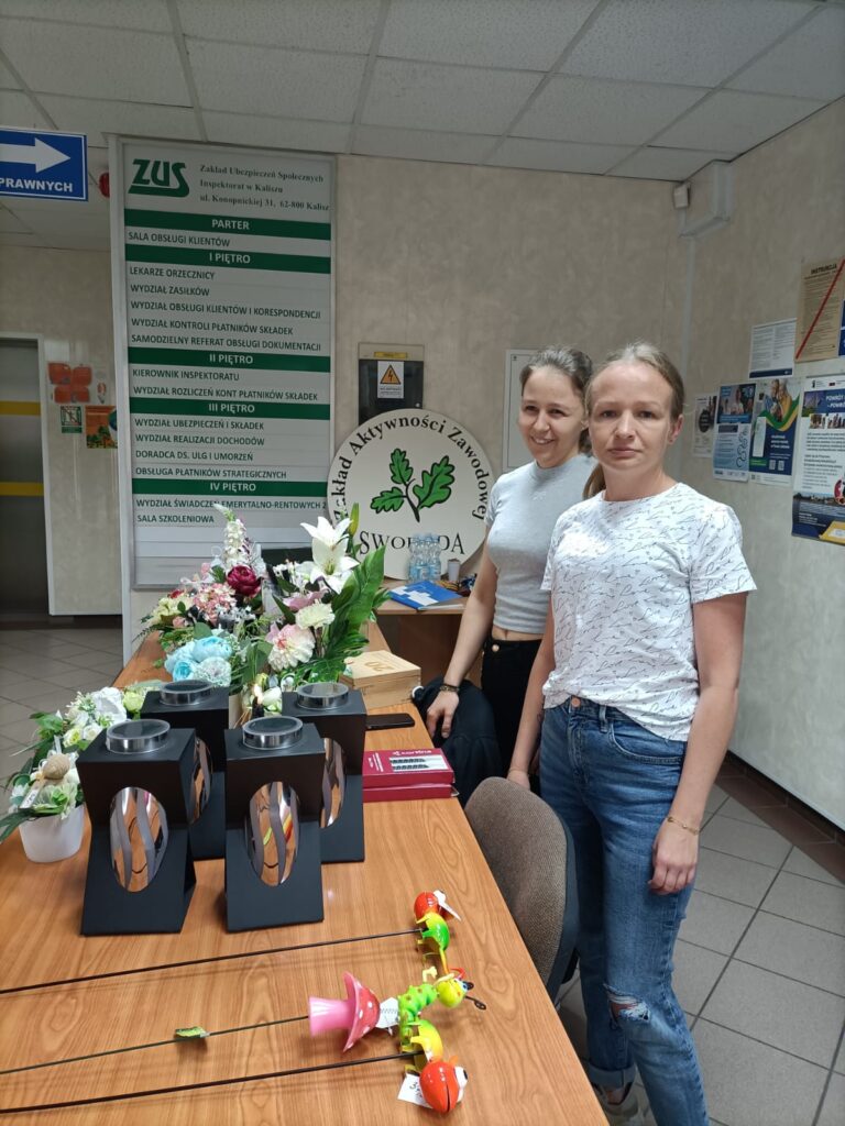 pracownice zakładu na wystawie naszego zakładu w ZUS w Kaliszu z kompozycjami kwiatowymi i zniczami solarnymi
