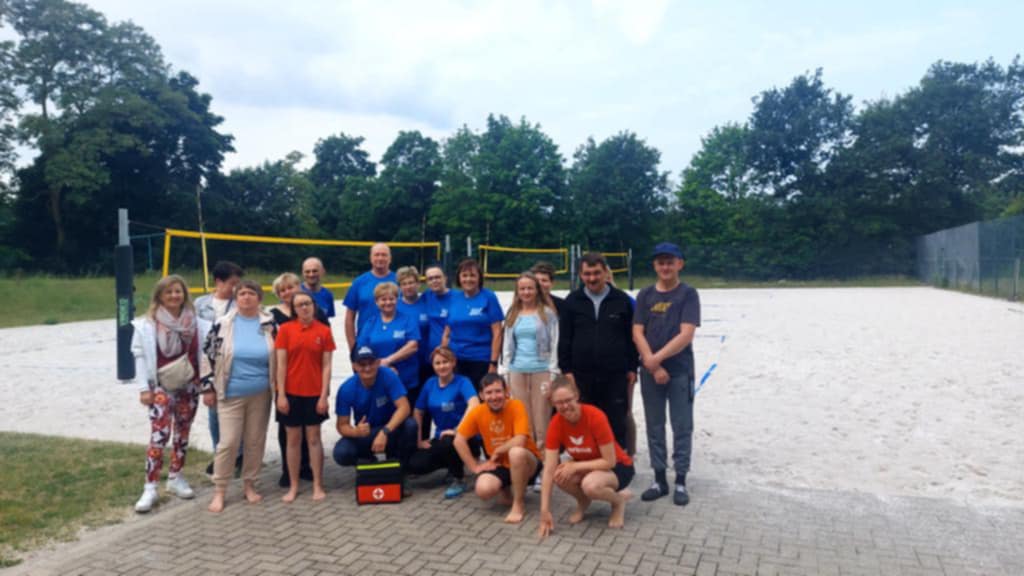 zdjęcie pracowników na tle boiska do piłki siatkowej
