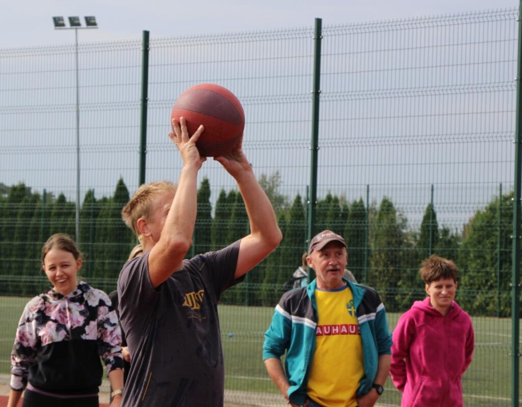 Pracownik zakładu strzela do kosza podczas spartakiady sportowej