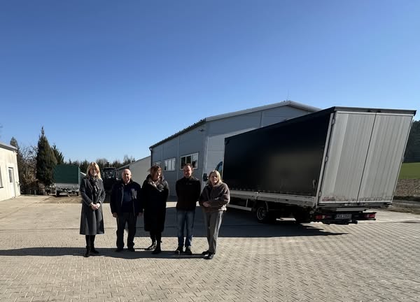 zdjęcie grupowe na tle busa i hali w zakładzie